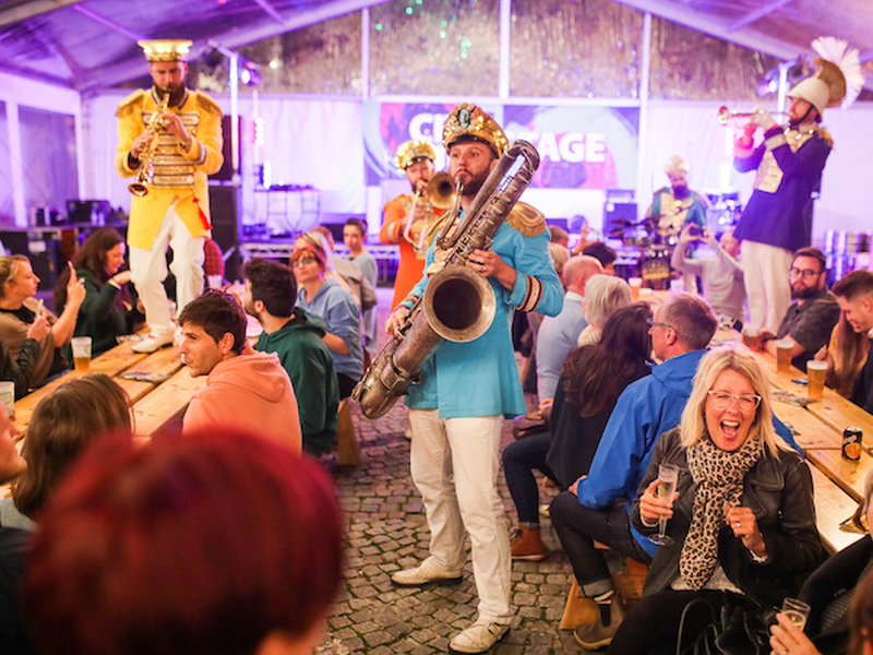 Brass Band Musicians Playing On Tables Among Diners At Mfdf