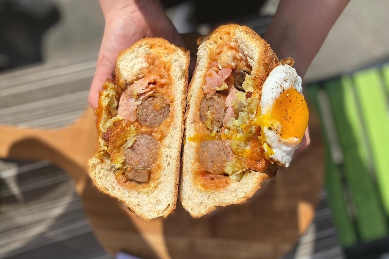 A Cross Section Of A Full English Stuffed Bread Roll With Runny Egg From Bread And Bowl Manchester