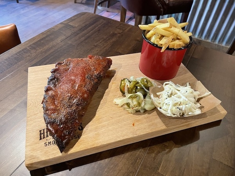 Smokehouse Ribs On A Board With Pickles Coleslaw And A Red Metal Cup Of Fries At Hickorys Wilmslow