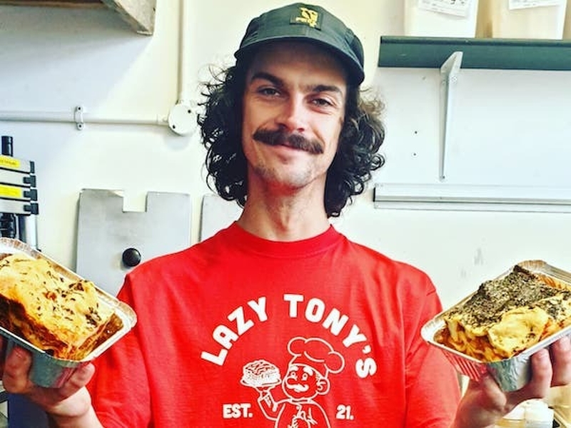 A Member Of Staff Sporting A Lazy Tonys Lasagneria T Shirt Whilst Holding Some Lasagne In Ancoats Manchester