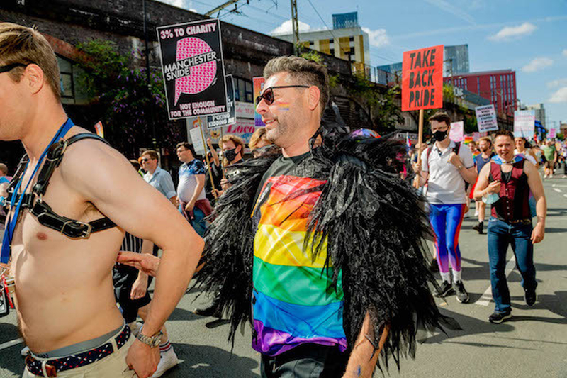 A Man In Ranbow Top And Black Feathers Marches At Manchester Pride Protest 2021 In Front Of Take Back Pride Sign Chris Keller Jackson