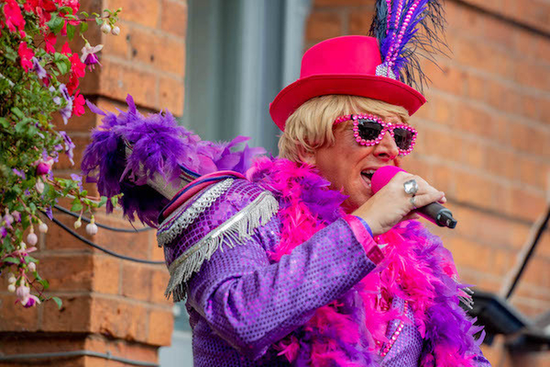 Ostentatious Performer In Purple And Pink Feather Sequin Shades And A Pink Hat At Manchester Pride 2021 Chris Keller Jackson