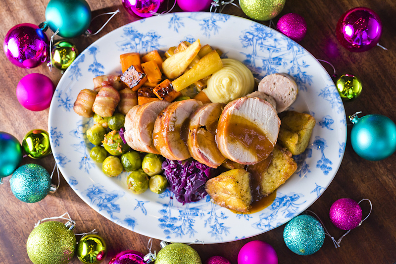 A Platter Of Roast Turkey Potatoes Pigs In Blankets And Xmas Verg From The Refuge Christmas Menu Surrounded By Colourful Baubles In A Modern Table Setting