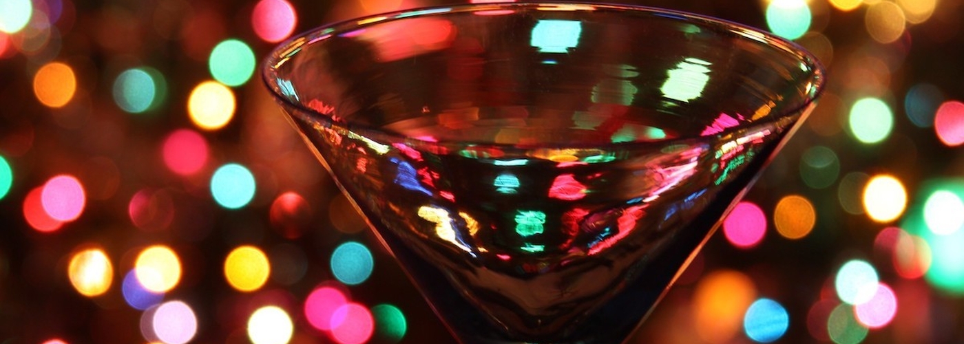 An Image Of A Martini Cocktail Glass With Xmas Fairy Lights In The Background