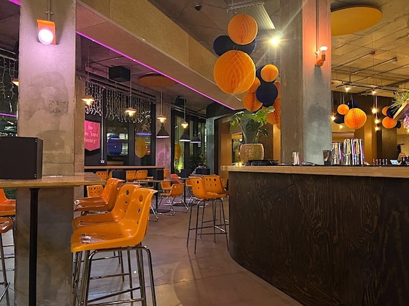 The Bright And Colourful Interior Of At Nells New York Pizza Bar Kampus Manchester With Orange Plastic Chairs And Chinese Lanterns On A Backdrop Of Concrete Brutalism