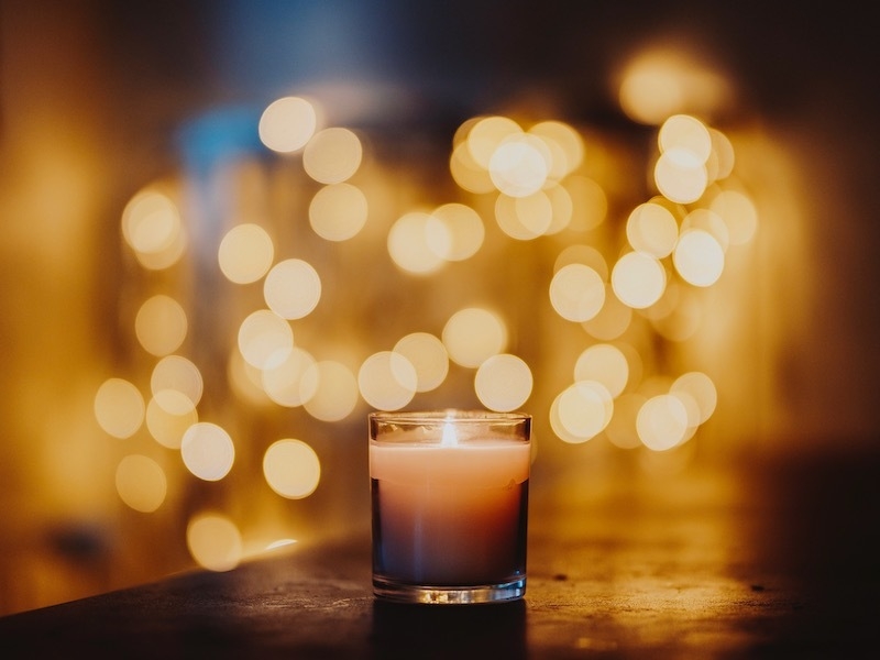A Candle In A Glass Jar Surrounded By Bokeh Effect Lighting