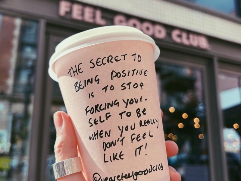 Takeaway coffee cup with a motivational quote outside Feel Good Club