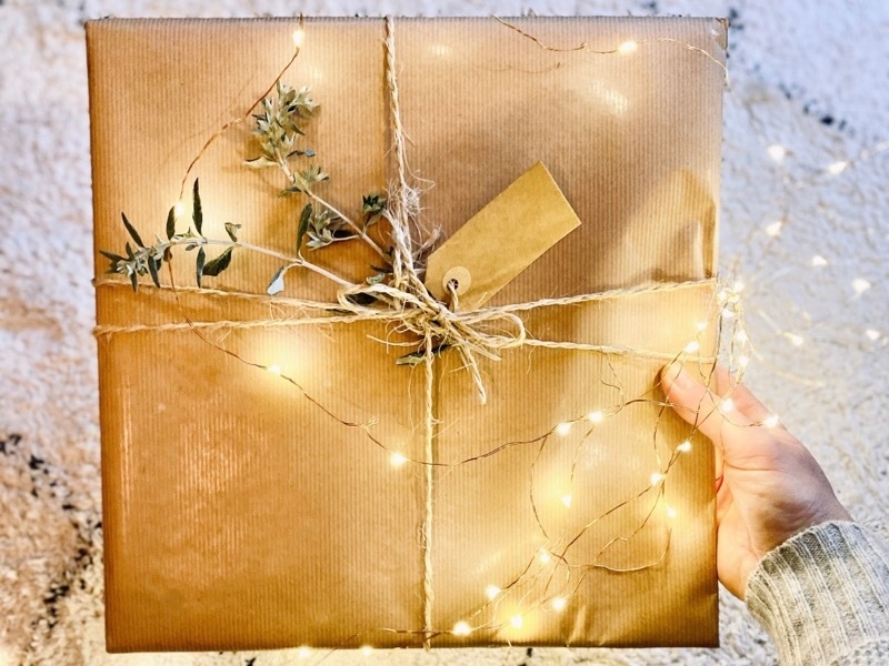 Girl holding Christmas present wrapped in brown paper