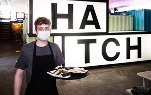 A Server Wearing Ppe Mask Holding A Tray Of Food At Hatch Manchester